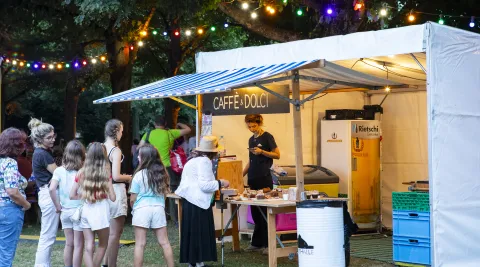Foodstand mit anstehenden Menschen und Lichterkette