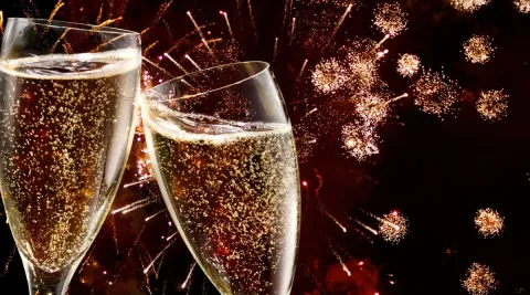 zwei Champagnergläser mit Feuerwerk im Hintergrund